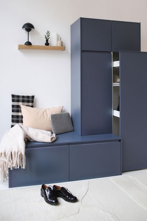 Meuble d'entrée sur mesure avec banquette intégrée bleu nuit Plum. Coussins, étagère en bois. Lampe noir.