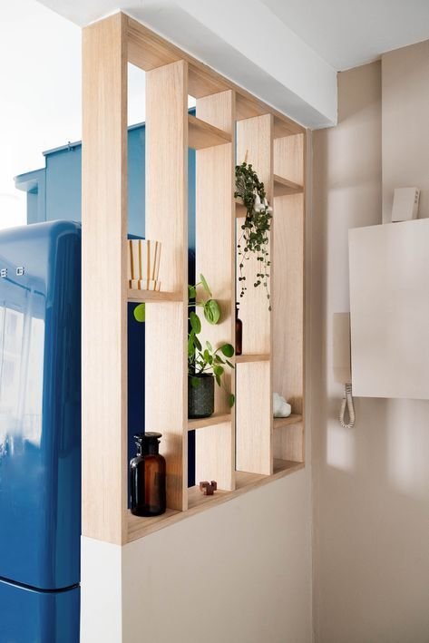 Idée pour bien aménager son entrée. Claustra d'entrée ouvert en bois sur demi-mur. Plantes vertes et vases.