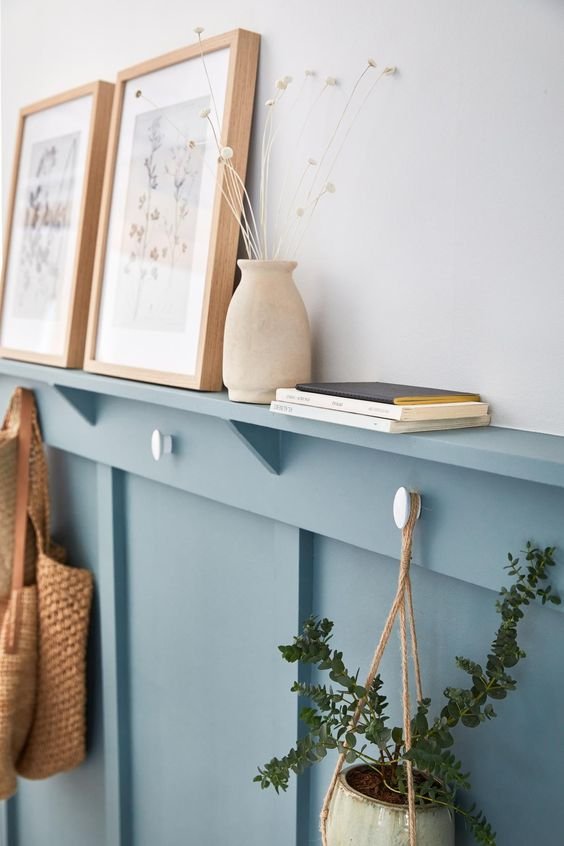 Comment bien décorer et aménager son entrée. Patère intégrée sur étagère mur. Cadres, vase et fleurs séchées. Bleu.