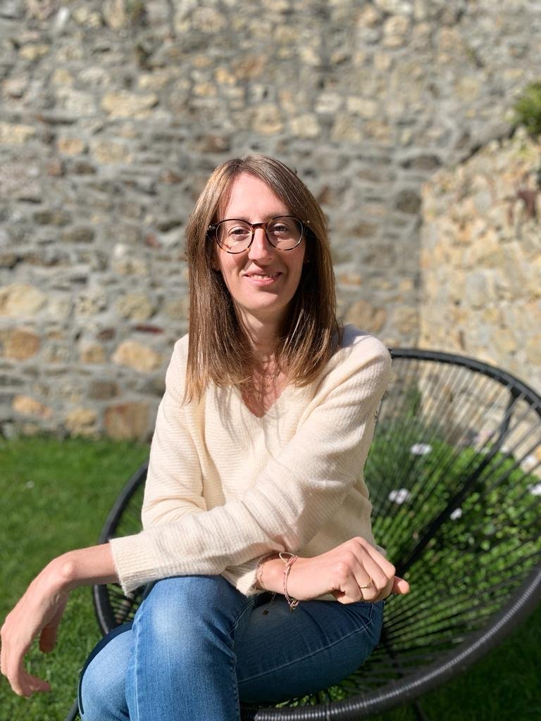 Portrait photographique en couleur de Clémence Coletti assise sur un fauteuil en extérieur.