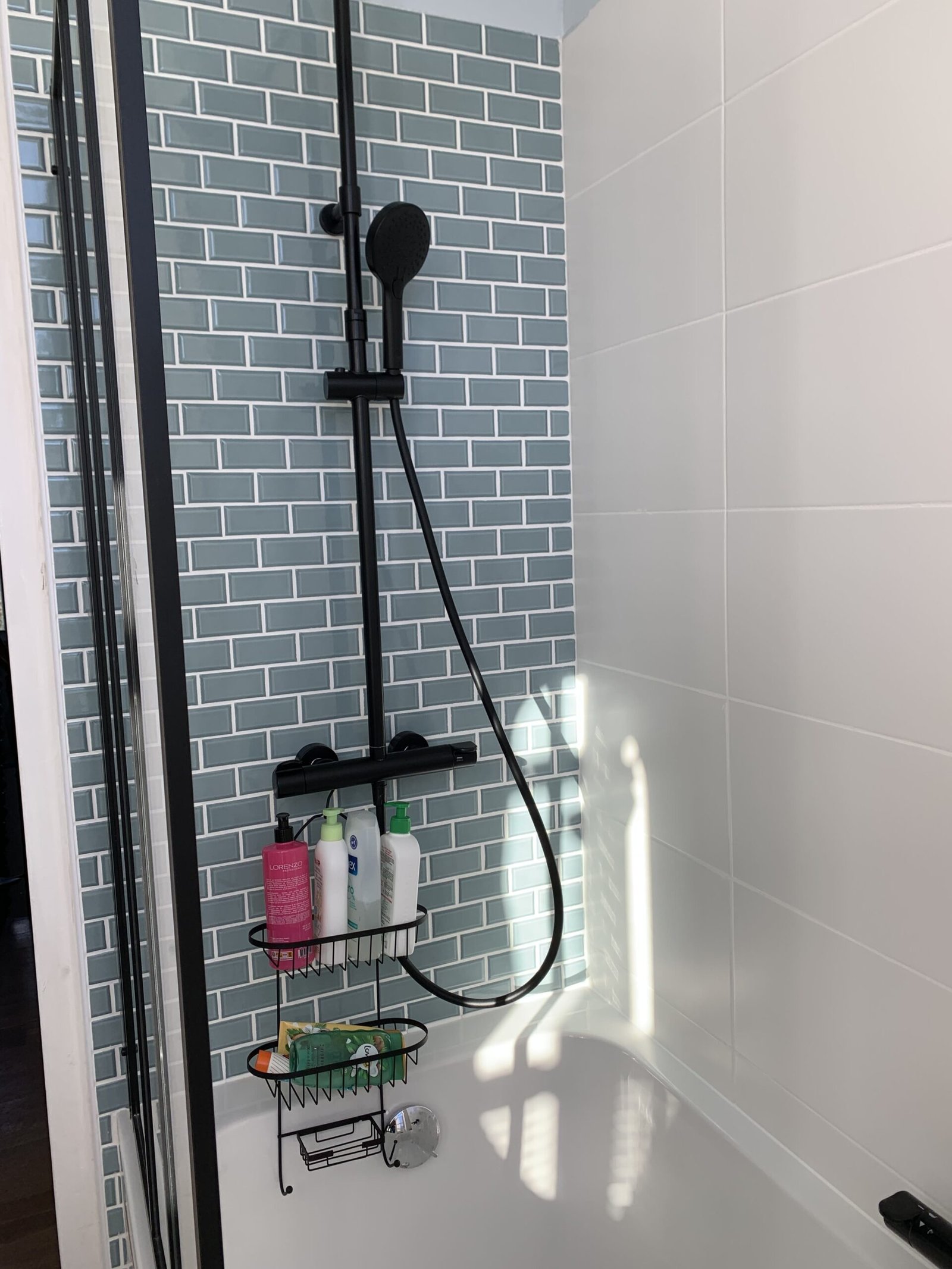 Photographie d'une salle de bain. Colonne de douche noir, parois atelier noire et baignoire blanche.
